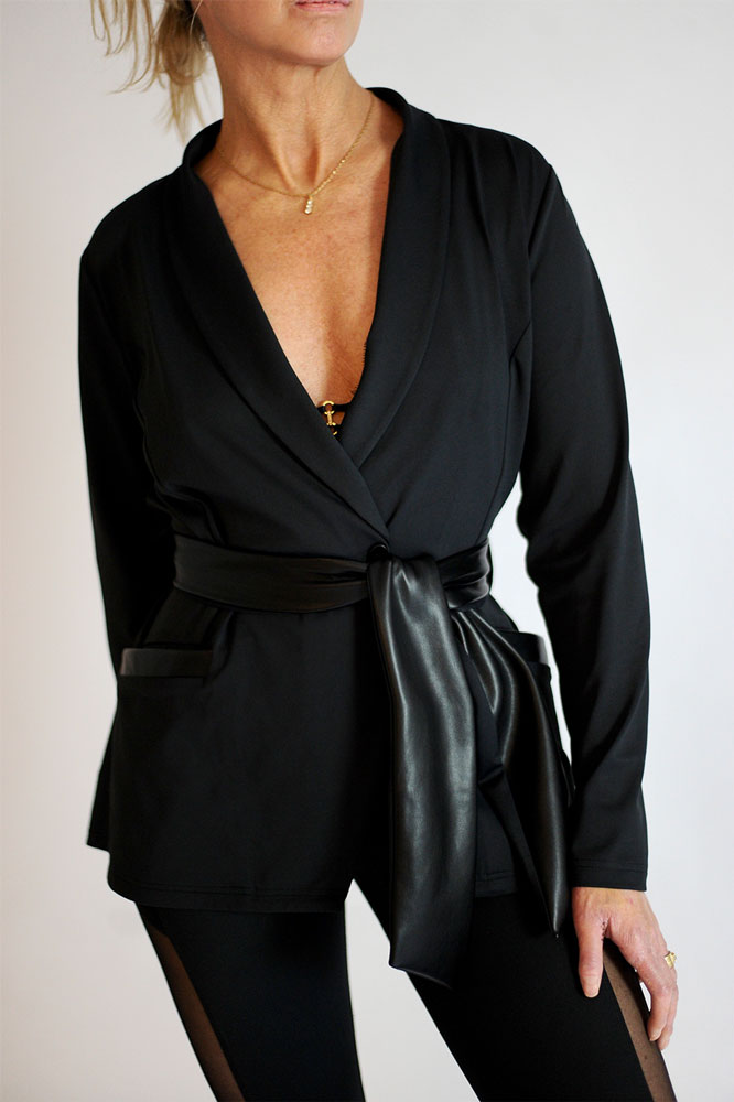 Il profondo collo a scialle e la cintura annodata da vicino. La modella porta una sottile collana color oro.