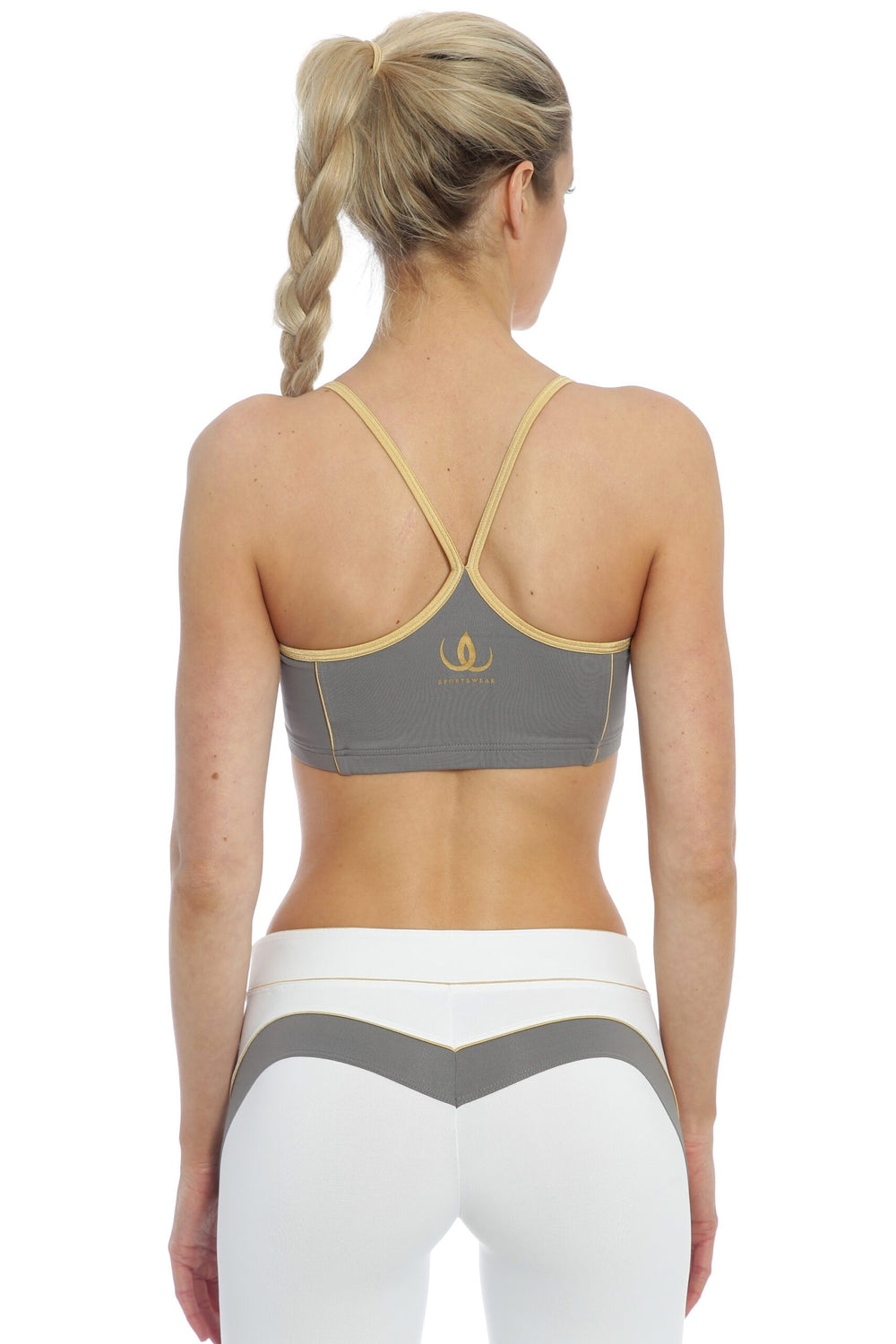 Narrow gold-edged straps meet in a Y across the back of the grey top, worn with white tights.