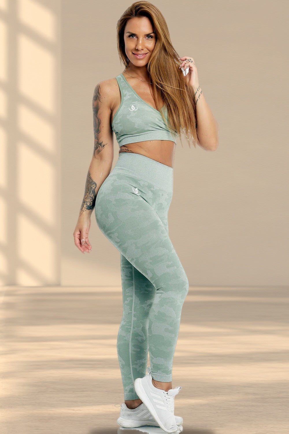 Het model staat in de mintgroene top en een legging met camouflageprint, met witte schoenen.