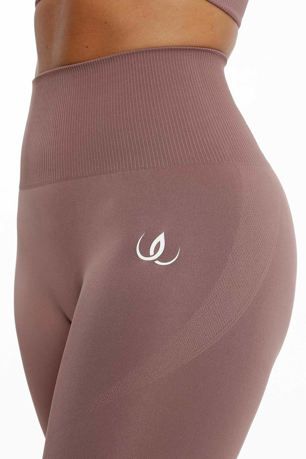 The ribbed waistband and the white logo at the hip, the fabric in a muted rose brown tone.