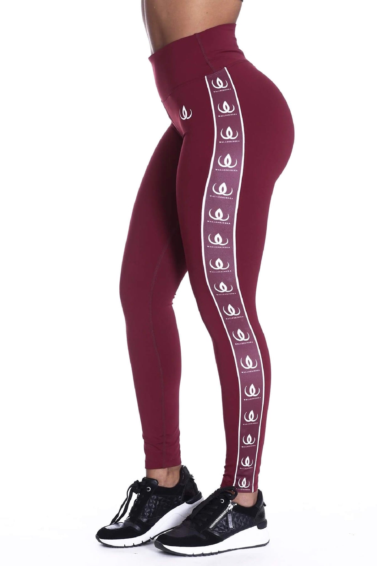 La vita alta dei leggings bordeaux, con fascia bianca con logo lungo il lato e scarpe nere in fondo.