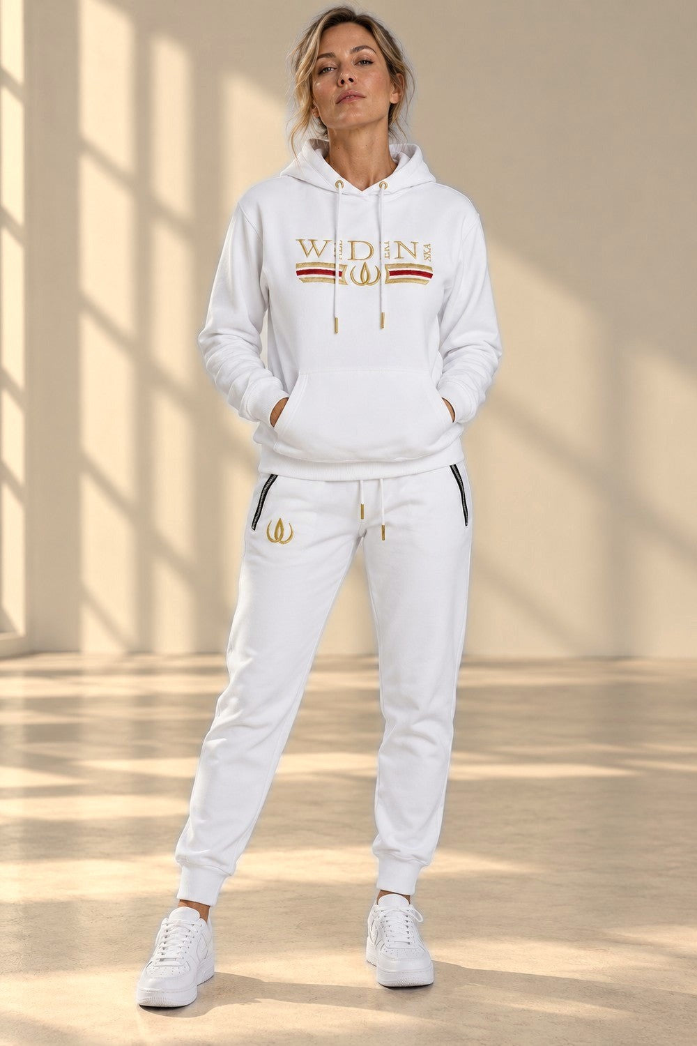 Vita Deluxe Joggers med guldlogga på låret och dragkedjor vid fickorna, buren till matchande hoodie.