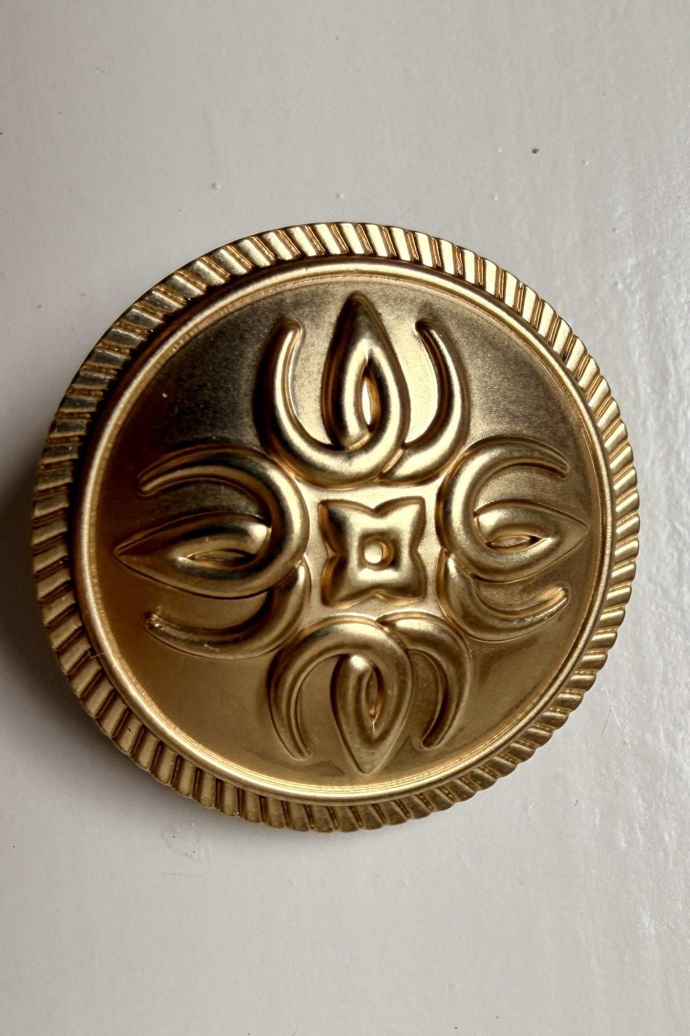 Close-up of the gold button, Wallderinska's V in four directions forming a flower