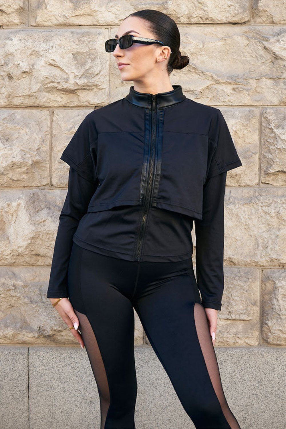 Edge black training jacket with a glossy collar and layers over the shoulders, worn with black leggings with mesh.