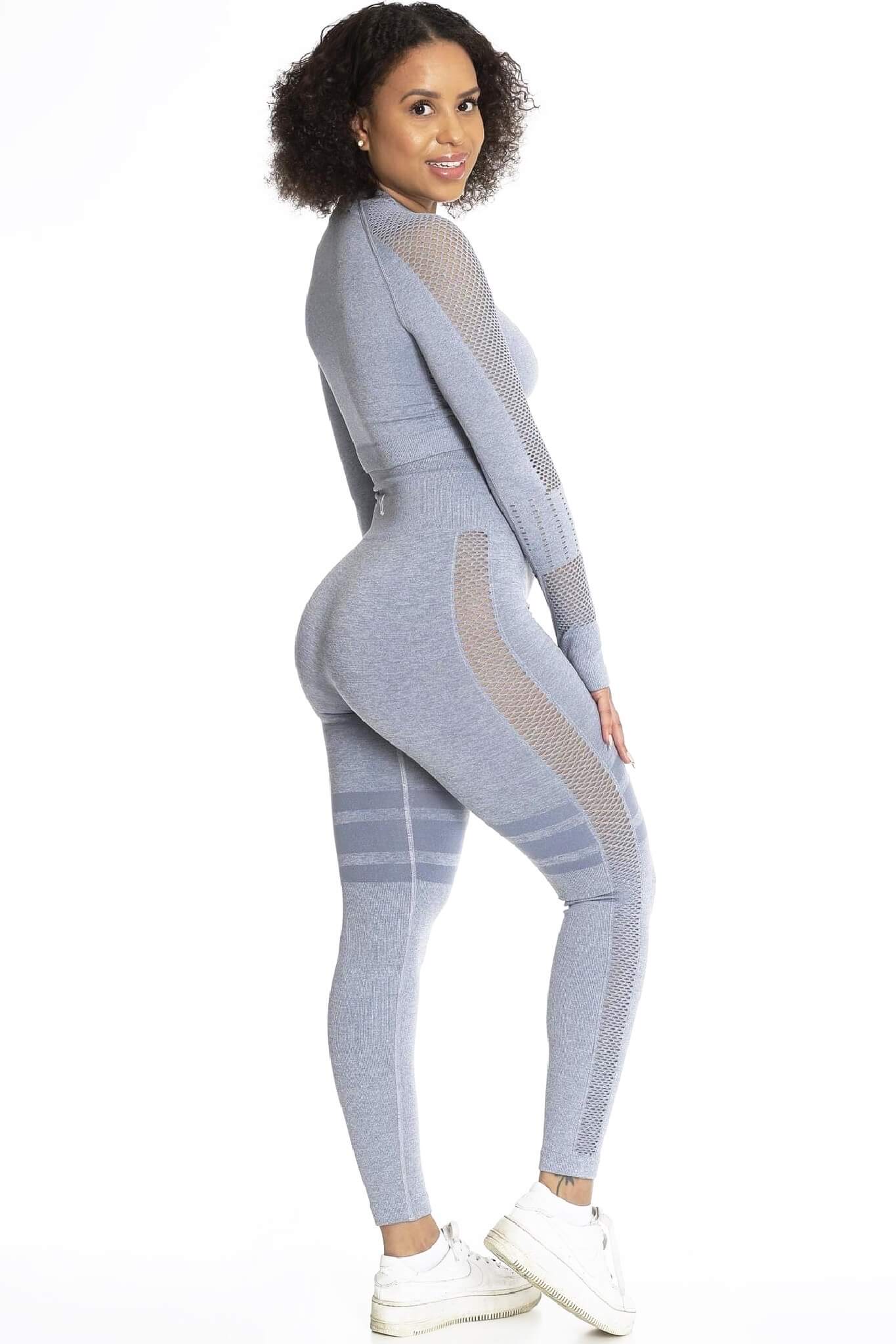 Tröjan bärs till matchande grå tights och vita sneakers. Modellen ser över axeln.
