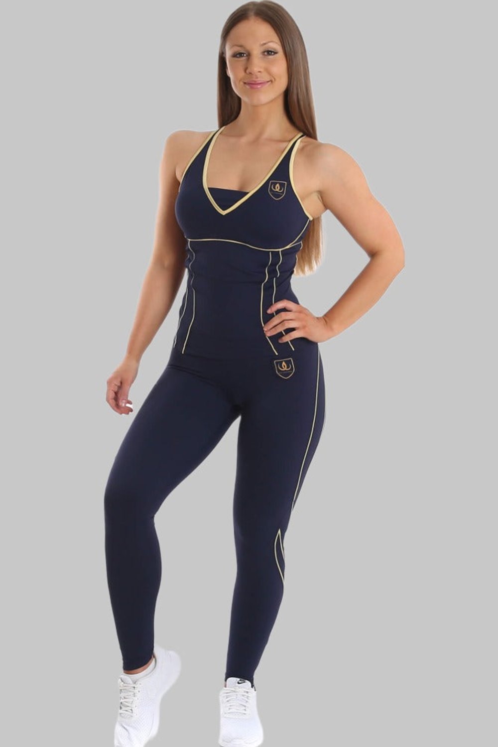 The model is standing in a navy vest and navy tights with gold lines, with white sneakers.