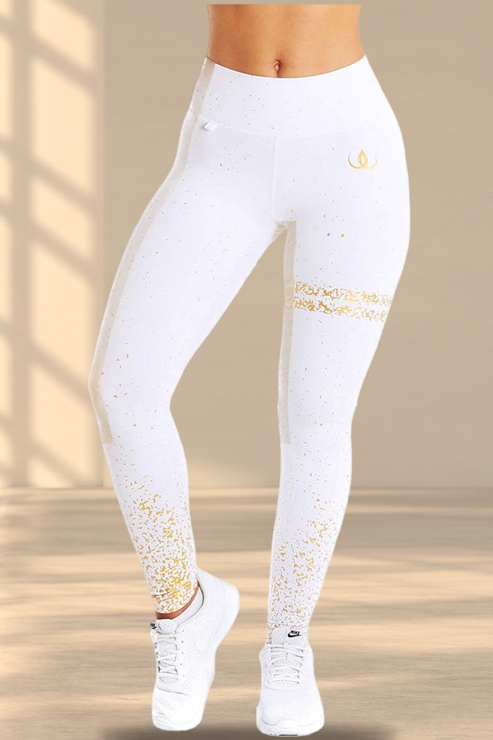 Witte legging met gouden spatten over de stof, een gouden band over het dijbeen en een gouden logo op de heup.